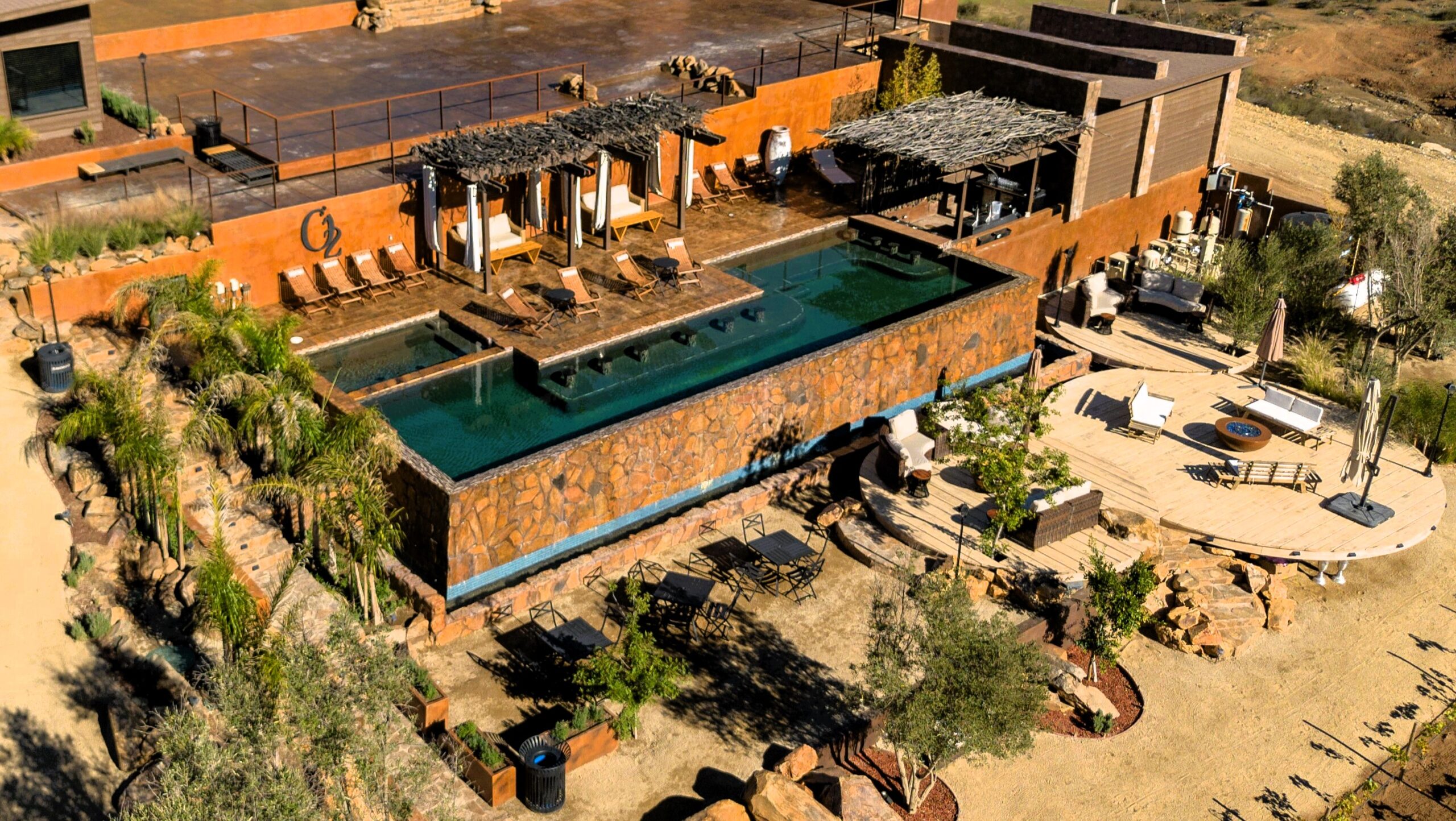 Aerial drone view of the luxury pool at O2 Resort Valle de Guadalupe surrounded by the scenic landscape of Baja California wine country