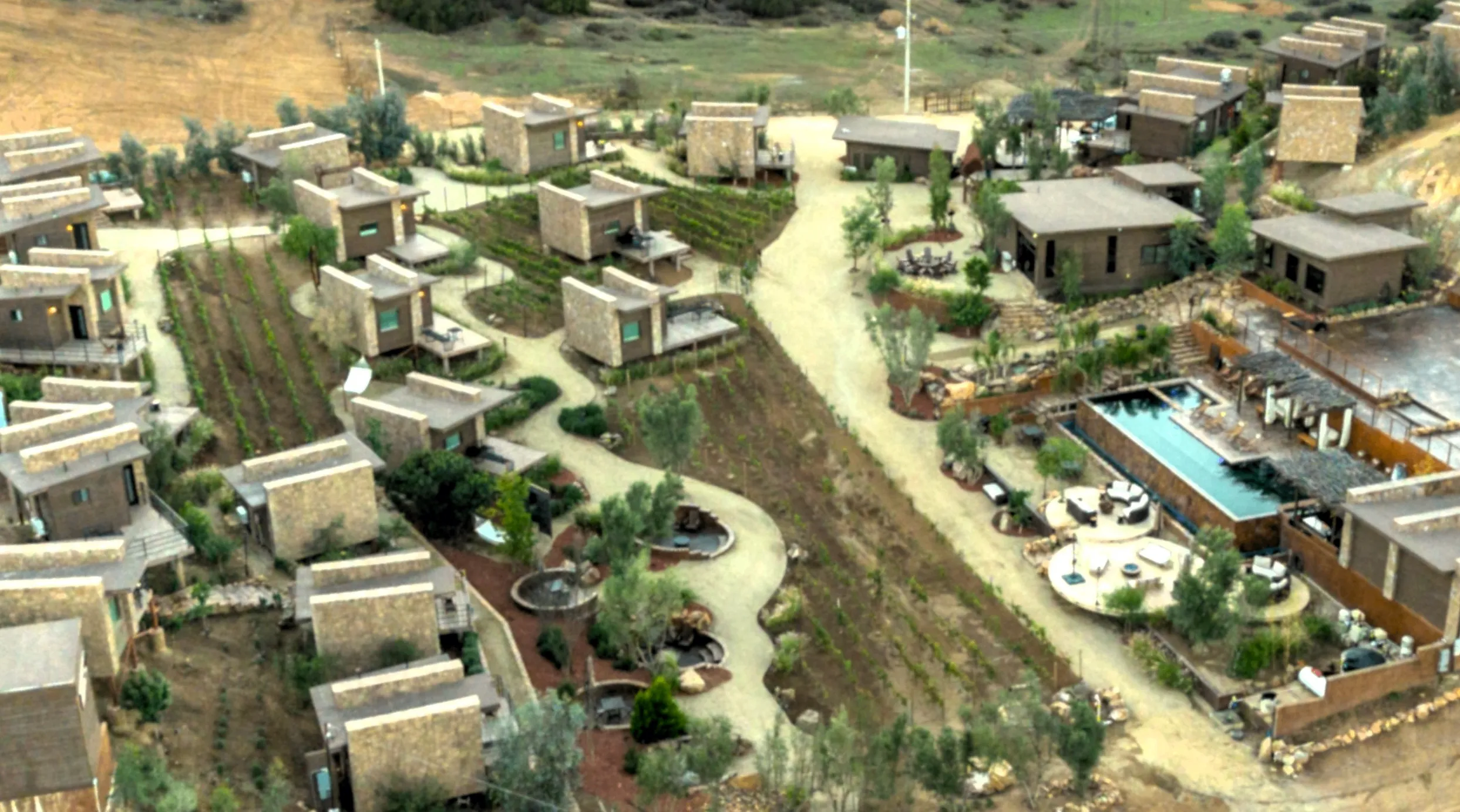 Aerial drone view of O2 Resort Valle de Guadalupe showing the resort cabins surrounded by the natural landscape of Baja California wine country