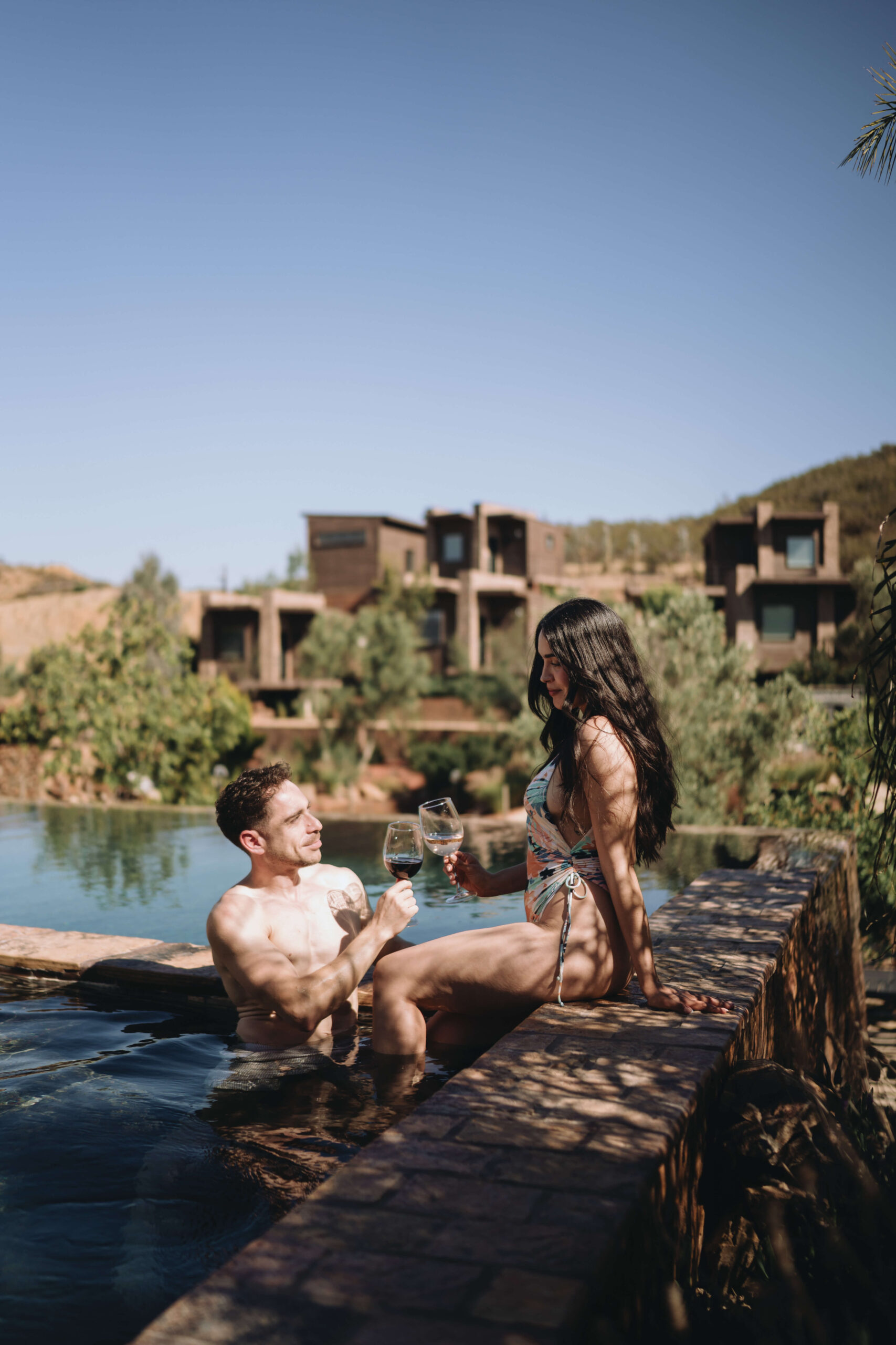 Couple relaxing by the infinity pool at O2 Resort Valle de Guadalupe enjoying a romantic getaway with panoramic vineyard views in Baja California wine country